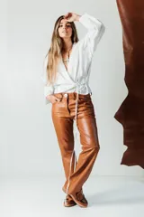 Pantalón de cuero de corte recto y tiro medio, color verde oscuro, con diseño artesanal y botón frontal.