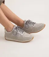 Championes de estilo runner retro de la marca Satinato, en tono gris con detalles plateados y suela de goma marrón. Cuentan con cordones estampados y combinación de materiales textiles y sintéticos.