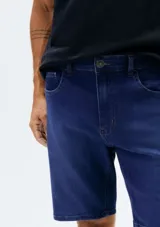 Bermuda de jean azul con diseño clásico de cinco bolsillos, cierre frontal con botón y bragueta, y costuras reforzadas.