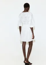 Vestido corto blanco de algodón con diseño broderie, escote en V con solapa, mangas cortas abullonadas y cintura elástica fruncida.