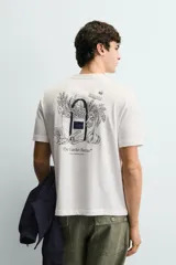 Camiseta de corte relajado, color blanco, con cuello redondo y manga corta. Presenta un pequeño estampado en el pecho con texto y un diseño gráfico más grande en la espalda.