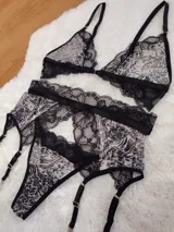Conjunto de lencería compuesto por corpiño triangular, bombacha tipo colaless y portaligas, confeccionado en encaje negro con estampado animal print.