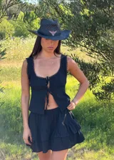 Falda corta negra con volados y short interno, confeccionada en tela liviana con textura sutil.