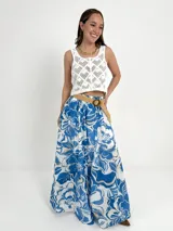 Falda larga de algodón con estampado floral en tonos azul y blanco. Tiene elástico en la cintura y viene con un cinto de rafia elastizado, desmontable.