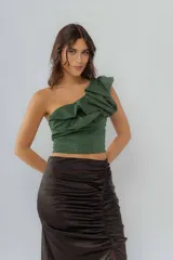 Top de un solo hombro confeccionado en tejido de lurex brillante color verde, con diseño de volados en el hombro y corte ajustado.