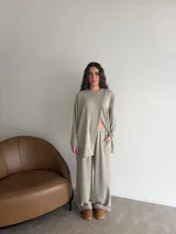 Conjunto de dos piezas color gris melange, confeccionado en tela de lanilla, compuesto por un buzo de manga larga con diseño cruzado al frente y un pantalón largo de corte holgado y tiro alto.