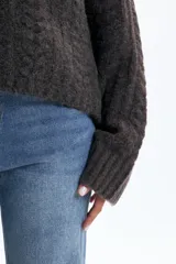 Polera de punto con diseño de textura fantasía, corte crop y cuello alto. Presenta mangas largas con puños acanalados y un calce holgado.