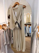 Conjunto de dos piezas para mujer en color beige, compuesto por un chaleco cruzado sin mangas con cinturón lateral y un pantalón de corte amplio.