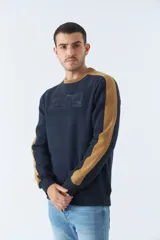 Buzo color bordó con cuello redondo y mangas largas con detalle de franja negra en los hombros. Tiene puños y logo "Mistral" estampado en relieve en el pecho.