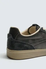 Zapatilla de estilo retro con diseño de paneles en cuero y serraje, cordones en tono crudo y suela de goma a contraste.
