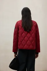 Campera acolchada de diseño matelasse con patrón de rombos, color rojo. Presenta cuello redondo, cierre frontal con botones a presión y mangas largas con puños de tejido acanalado.