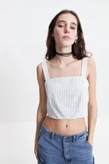 Top corto a rayas verticales azules y blancas, con escote recto y tirantes anchos.