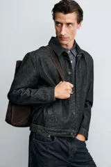 Cazadora de denim de algodón en color negro, de corte regular fit, con cuello solapa, cierre frontal de botones metálicos, mangas largas con puños abotonados y bolsillos laterales de vivo.