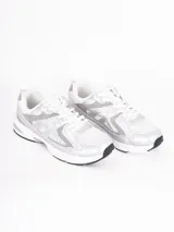 Zapatillas deportivas de estilo urbano, color blanco con detalles en plateado, confeccionadas en malla y material sintético, con suela de goma.