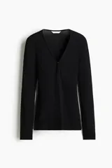 Top negro de manga larga en tejido de punto acanalado fino. Presenta un escote en V profundo con una pequeña abertura frontal cerrada con dos corchetes ocultos.