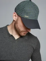 Gorra tipo baseball con visera rígida, confeccionada en tela a cuadros color verde, azul y beige.