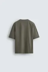 Camiseta boxy fit color verde militar con efecto lavado, confeccionada en tejido compacto de algodón con cuello redondo y manga corta.