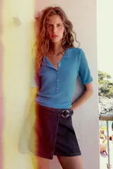 Falda pantalón cruzada de denim en color celeste, con diseño cruzado al frente, cierre frontal oculto y hebilla decorativa redonda en la cintura.
