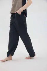 Pantalón de lino color beige, de silueta relajada, tiro medio-alto, cintura elastizada con cordón ajustable, bolsillos laterales y bolsillos traseros.