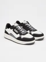 Championes urbanos Rusty modelo Meier, con diseño de paneles en colores blanco, negro y gris. Presentan cierre de cordones, puntera perforada para mayor ventilación y suela de goma plana.