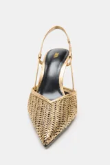 Zapato de tacón alto destalonado en color dorado con acabado metalizado y diseño de efecto trenzado. Presenta una tira trasera con elástico y puntera fina.