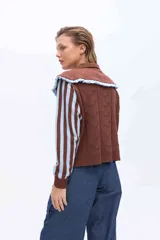Buzo de punto color rosado con mangas largas a rayas marrones y rosadas. Presenta un doble cuello XL en color rosado con borde marrón y terminación de rulo, además de un cuerpo con detalles de calados y puntos tejidos.