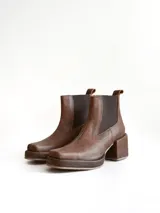 Bota tipo chelsea de cuero color chocolate con acabado texturizado, plataforma y taco cuadrado. Presenta paneles elásticos laterales en color negro.