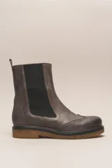 Bota tipo Chelsea de cuero vacuno color suela, con diseño brogue en la puntera y laterales. Presenta paneles elásticos laterales en color marrón oscuro, tirador trasero y suela de goma con plataforma.
