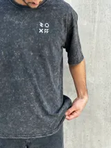 Remera gris con efecto gastado, corte oversize, mangas cortas y estampado en la espalda con el texto "SUPPLY GOODS DESIGNED IN PUNTA DEL ESTE".