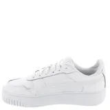 Championes urbanos Puma modelo Carina Street, color negro con suela de plataforma blanca. Presentan diseño de cuero sintético con cordones al tono y logo de la marca en color cobre en el lateral.