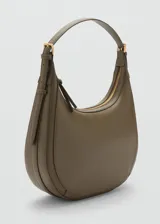 Bolso de hombro tipo hobo con diseño curvo y minimalista. Presenta un asa ajustable con hebillas laterales y cierre superior de cremallera.