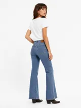 Jean de denim azul de corte flare, con tiro medio, diseño de botamanga acampanada y sutil estampado texturizado en toda la prenda.