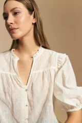 Camisa blanca de manga corta abullonada con terminación elastizada y cuello con leve frunce. Presenta una estampa floral integral.