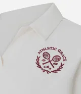 Remera polo deportiva de manga corta, confeccionada en poliamida y elastano. Presenta cuello polo con escote en V y un bordado temático de tenis con la inscripción 'Athletic Grace' en el pecho.