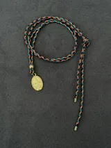 Collar con cordón trenzado multicolor en tonos marrón, celeste y rosado con hilo dorado, y dije ovalado dorado con relieve de la Medalla Milagrosa.