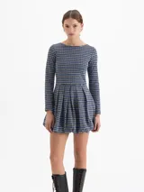 Vestido corto de punto con estampado de cuadros tipo príncipe de gales en tonos azul, negro y blanco. Presenta escote redondo, mangas largas y falda con diseño balloon que aporta volumen. Cuenta con espalda abierta con tiras cruzadas.