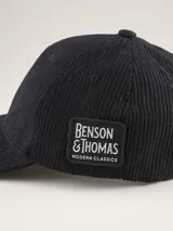 Gorra tipo baseball confeccionada en pana color azul marino, con parche rectangular lateral que incluye el logo de la marca Benson & Thomas.