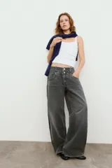 Jeans de tiro medio con cinco bolsillos, cintura doble a contraste y detalles de rotos. Cierre frontal con cremallera y botones metálicos.