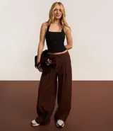 Pantalón wide leg de estilo sastre color marrón, con cintura elástica, lazo ajustable y pliegues frontales. Presenta un corte recto y fluido.