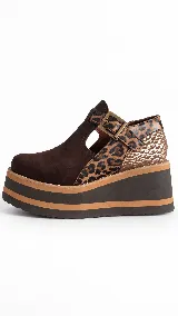 Guillerminas de cuero marrón chocolate, con detalles en animal print y textura dorada metalizada. Presentan una tira con hebilla metálica en el empeine, aberturas laterales y suela de plataforma corrida con franjas en contraste.