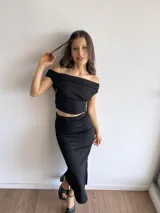 Top negro de tela bambula elastizada, con diseño off-shoulder y corte ajustado al cuerpo.