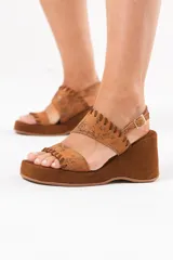 Sandalia de taco chino y plataforma forrada, confeccionada 100% en cuero color tostado con acabado metalizado texturizado en la capellada y detalles de costuras artesanales. Cuenta con doble tira superior y tira trasera ajustable con hebilla metálica.