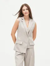 Chaleco largo color visón con solapas, sin mangas, con bolsillos frontales y cierre con dos botones.