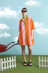 Túnica de algodón con diseño de rayas verticales multicolor en tonos celeste, marrón y fucsia. Presenta cuello polo, manga corta y cierre frontal con botones.