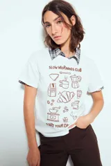 Remera blanca de manga corta, con estampa frontal en color marrón con motivos de café y la leyenda 'Slow Mornings Club'.