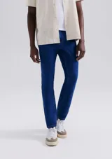 Pantalón de jean de corte slim, color azul, con cierre de botón y cremallera, y bolsillos laterales y traseros.