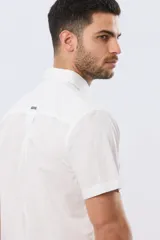 Camisa lisa de algodón azul marino, de manga corta, con cuello camisero, cierre frontal de botones y un bolsillo aplicado en el pecho.