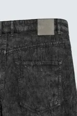 Pantalón de corte baggy fit confeccionado en tejido de algodón con textura y efecto lavado. Presenta diseño de cinco bolsillos, cierre frontal con cremallera y botón.