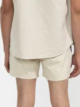 Short de baño para hombre color azul marino, con calce relajado y una tira lateral blanca estilo tuxedo. Presenta cintura elástica con cordón regulable, bolsillos laterales y trasero con cierre.