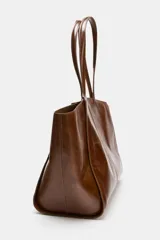 Bolso tipo shopper confeccionado en piel, con diseño de doble asa de hombro y cierre mediante botón imantado. Incluye bolsillo interior.